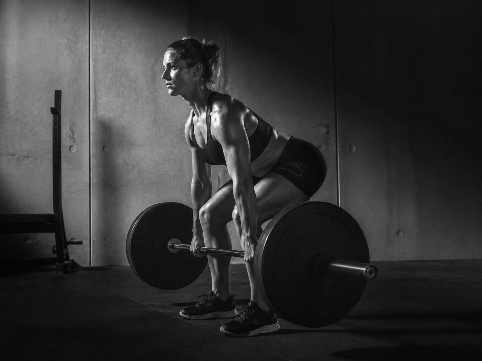 Athlete performing a barbell deadlift in a minimal concrete gym